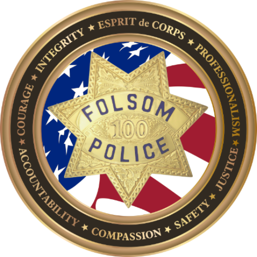 Folsom Police Department badge with a gold star displaying 'Folsom Police 100' over a stylized American flag, surrounded by a gold ring with words like Integrity, Courage, Compassion, and Justice.