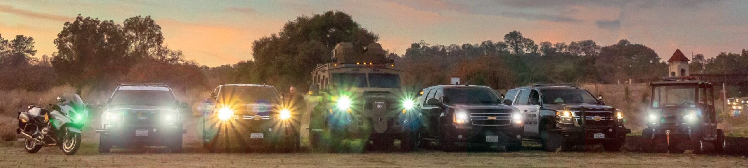 a group of police vehicles all in a line with their lights turned on